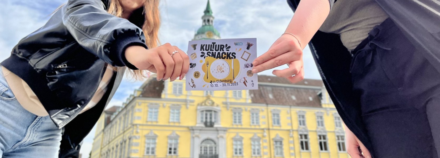 Die Auszubildenden Mariia Strateichuk und Merle St&uuml;hrenberg der OTM pr&auml;sentieren die Postkarte zum Start der Kultursnacks 2023.