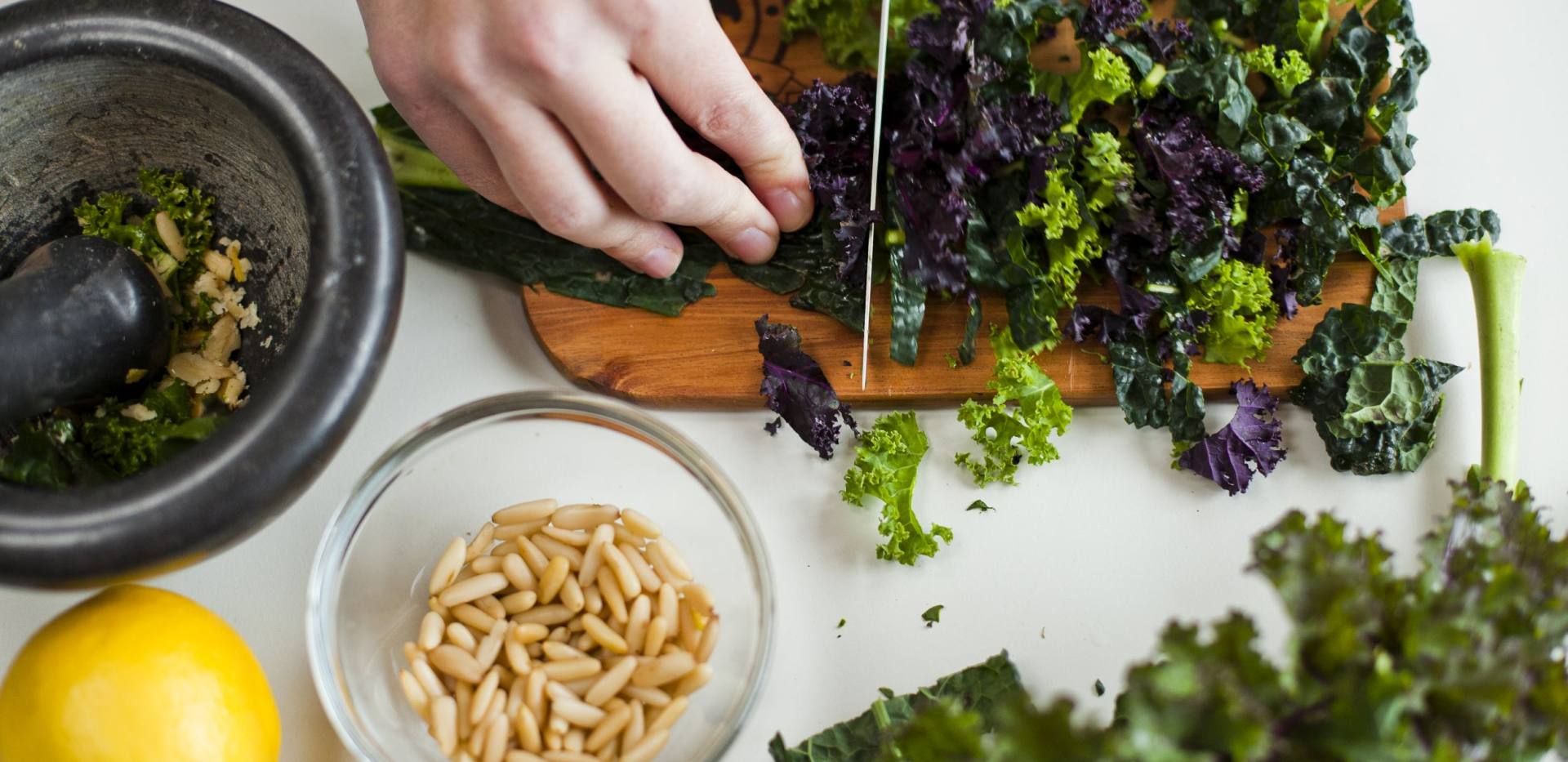 Schneiden einer Gr&uuml;nkohlpflanze und weitere Zutaten daneben. 