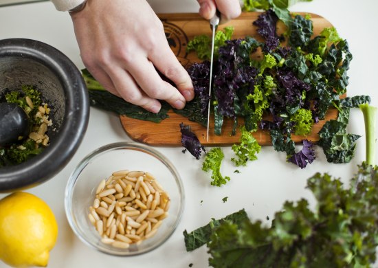 Schneiden einer Gr&uuml;nkohlpflanze mit weiteren Zutaten daneben. 