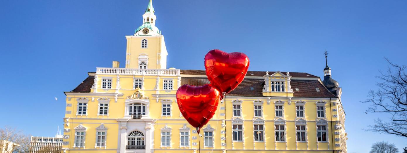 Blick auf das Schloss Oldenburg mit Herzluftballons davor.