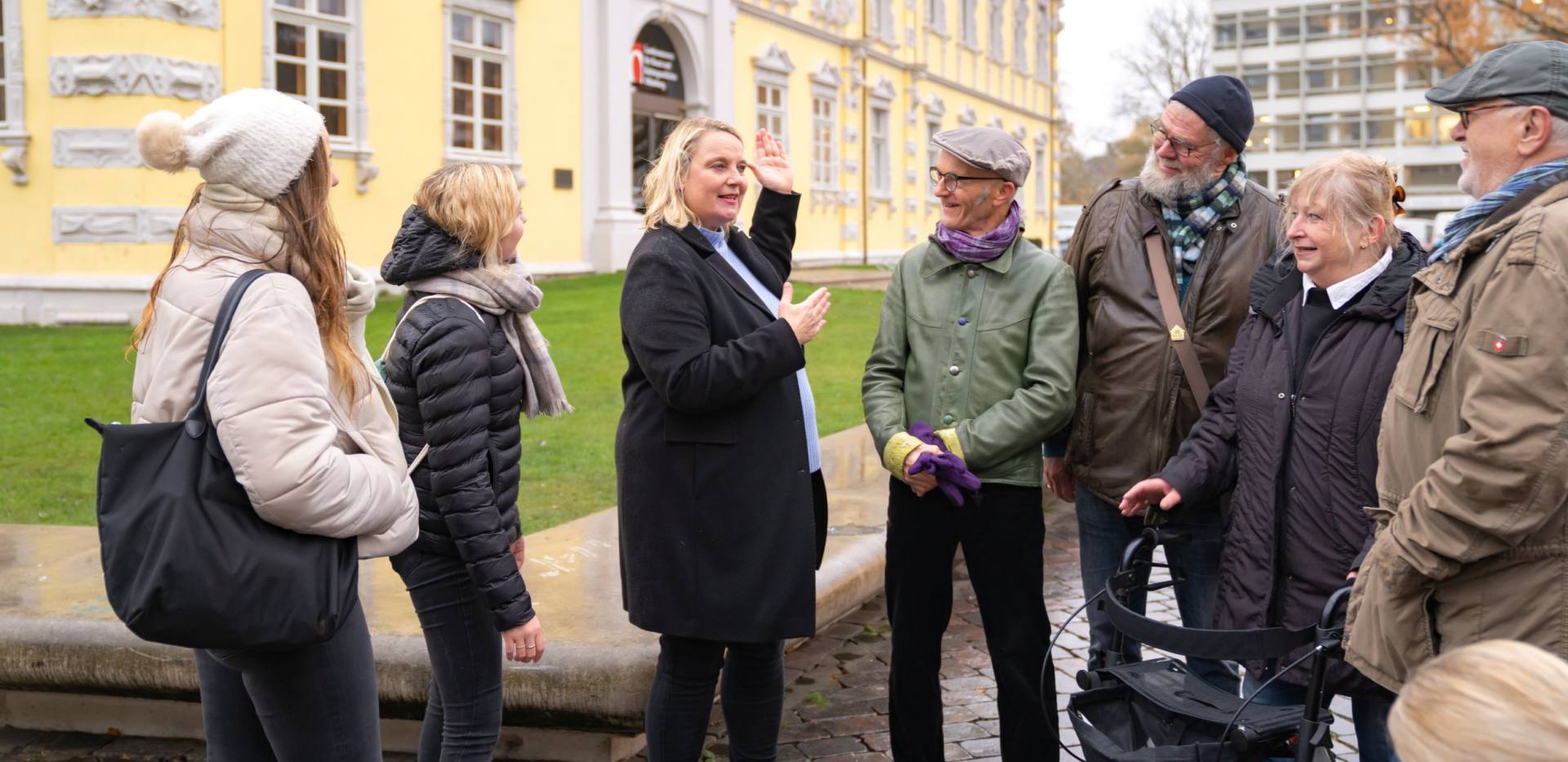 Gästeführerin Maike Vormelker mit Teilnehmerinnen und Teilnehmern mit und ohne Beeinträchtigung bei einer Stadtführung. 