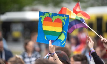 Weltkarte mit Herz in Regenbogenfarben wird hochgehalten während des CSD Nordwest.