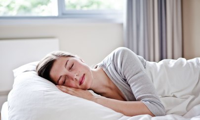 Eine Frau liegend schlafend in einem Hotelbett.