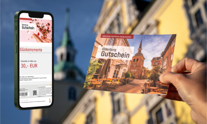 Klappkarte des Gutscheins vor dem Schloss mit Smartphone und digitaler Gutscheinvariante im Display.