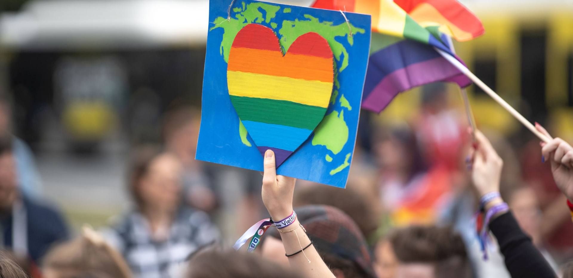 Weltkarte mit Herz in Regenbogenfarben wird hochgehalten während des CSD Nordwest.
