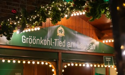 Schild an der Holzbude "Gr&ouml;&ouml;nkohl-Tied am Lappan" und Weihnachtsschmuck.