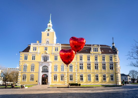 Blick auf das Schloss Oldenburg mit Herzluftballons davor.