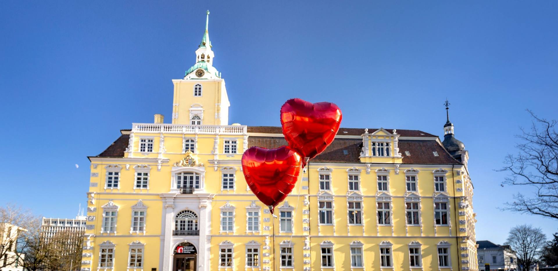 Blick auf das Schloss Oldenburg mit Herzluftballons davor.