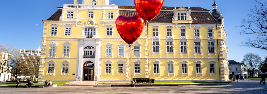 Blick auf das Schloss Oldenburg mit Herzluftballons davor.