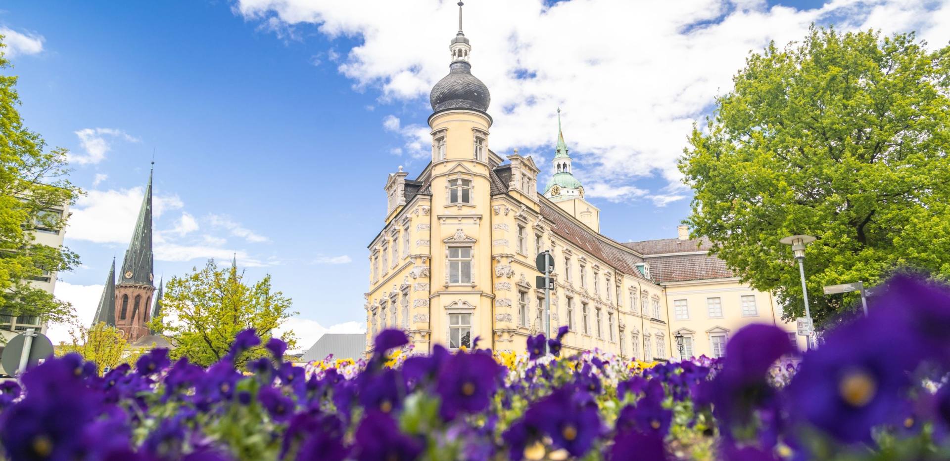 Schloss und die St. Lamberti-Kirche mit Blumen im Vordergrund. 