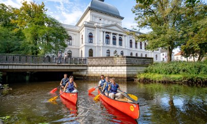 Zwei Kanus mit Stadtführungs-Teilnehmern, die „City Paddeln“ machen. Sie fahren auf der Hausbäke vor dem Oldenburgischen Staatstheater.