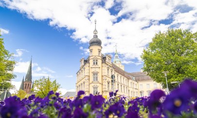 Schloss und die St. Lamberti-Kirche mit Blumen im Vordergrund. 