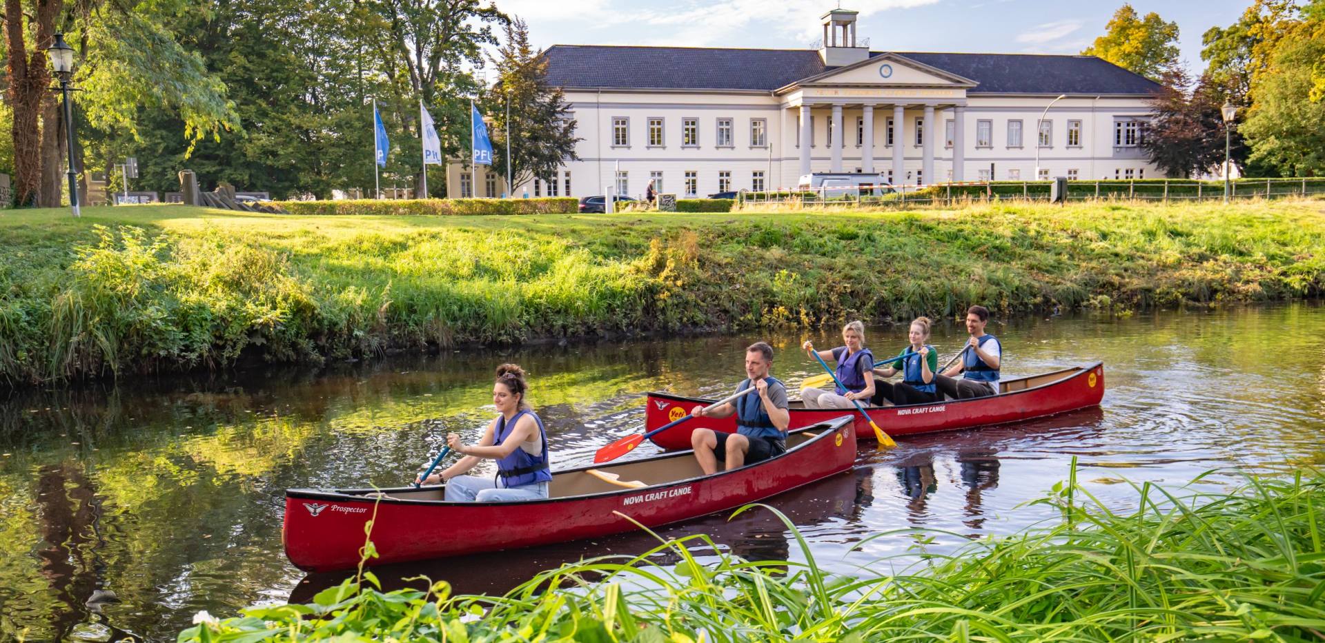 Zwei Kanus mit Teilnehmenden der Stadtf&uuml;hrung &bdquo;City Paddeln&ldquo;. Sie fahren auf der Haaren in den Wallanlagen vor dem Kulturzentrum PFL in Oldenburg.