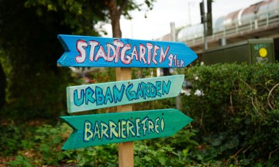 Hinweisschild aus Holz im Stadtgarten "Urban Gardening" 2025.