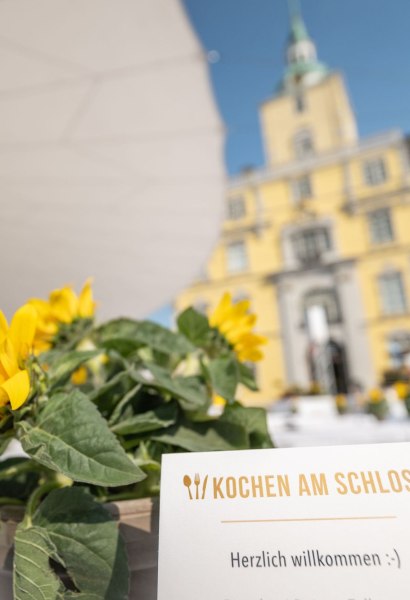 Gedeckte Tische auf dem Schlossplatz in Oldenburg für die Veranstaltung "Kochen am Schloss" mit Schloss im Hintergrund. 