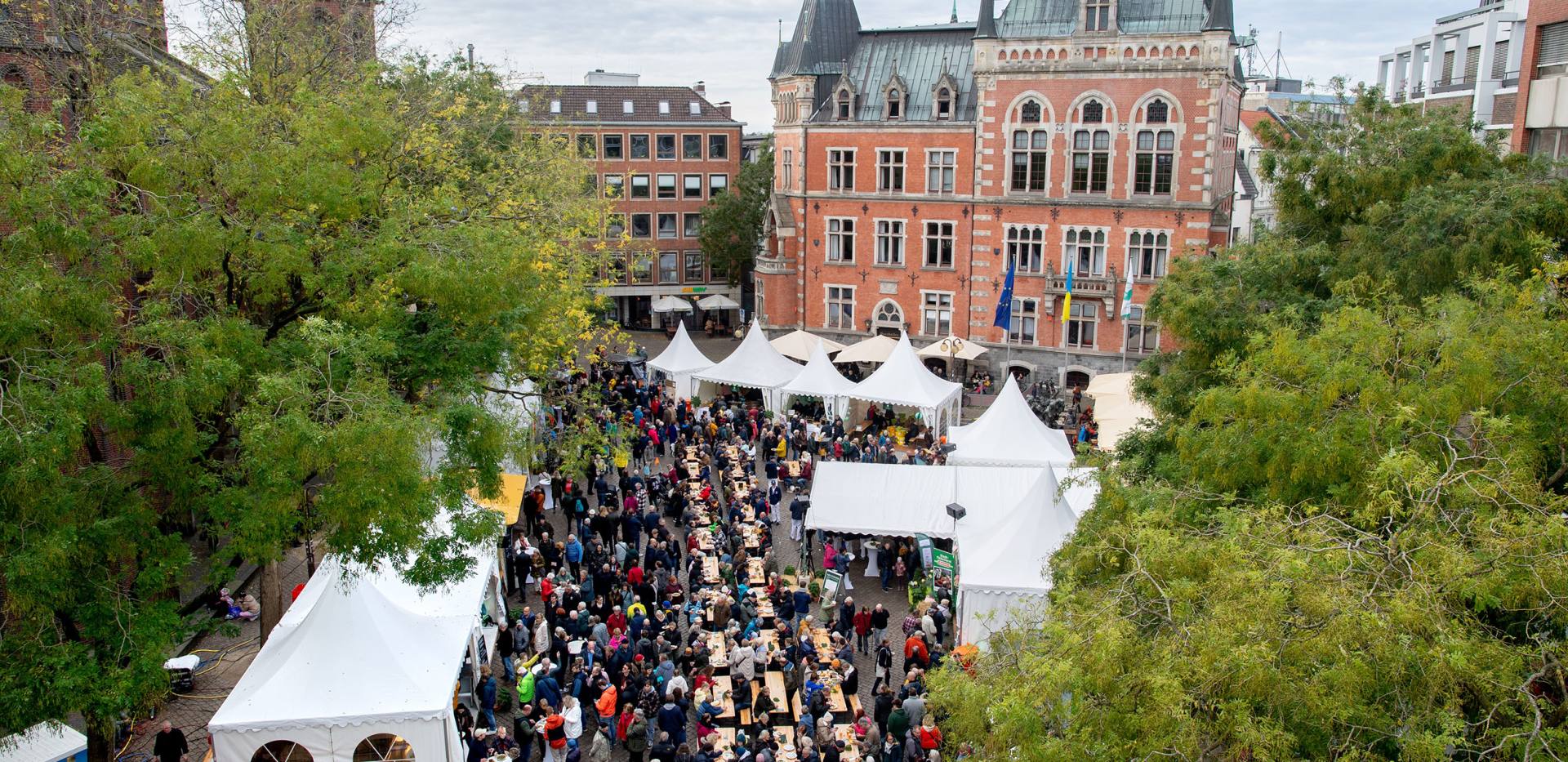 Auf dem Oldenburger Rathausmarkt sind zu hallo Grünkohl viele Stände und lange Sitzreihen zum Essen aufgebaut.