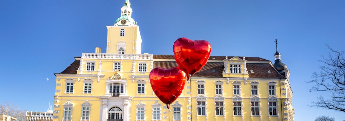 Blick auf das Schloss Oldenburg mit Herzluftballons davor.
